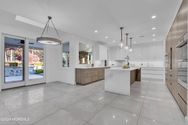 kitchen featuring decorative light fixtures, white cabinets, light tile patterned floors, and a spacious island