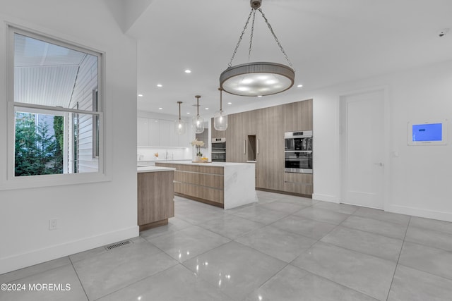 kitchen with double oven, hanging light fixtures, and a center island