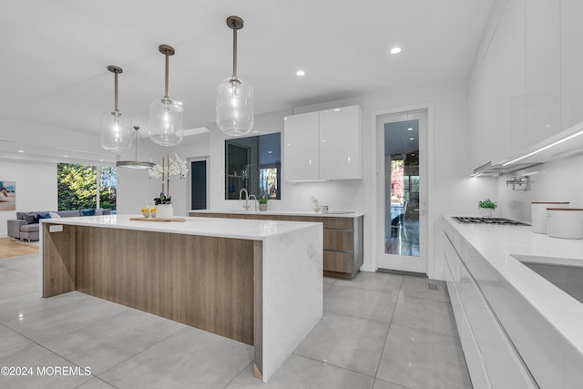 kitchen featuring sink, white cabinets, pendant lighting, and a large island