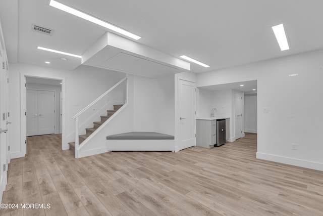 basement with sink and light hardwood / wood-style flooring