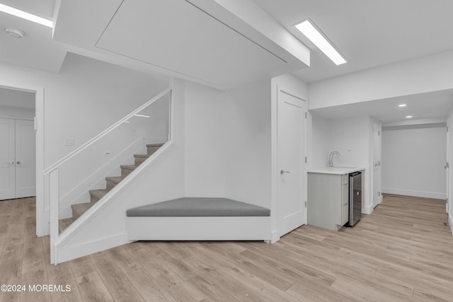 stairs with beverage cooler and hardwood / wood-style floors