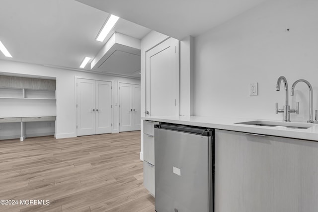 kitchen with light hardwood / wood-style flooring, dishwashing machine, and sink