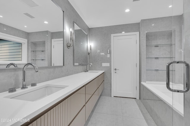 bathroom with tile walls, a bathing tub, tile patterned floors, and vanity