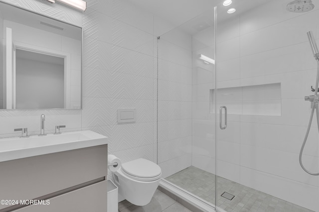 bathroom featuring toilet, tile patterned flooring, tile walls, a shower with shower door, and vanity