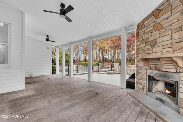 wooden deck with ceiling fan and an outdoor stone fireplace