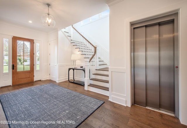 entrance foyer featuring elevator, a chandelier, dark hardwood / wood-style flooring, and ornamental molding