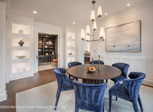 dining room featuring hardwood / wood-style floors, a chandelier, ornamental molding, and built in shelves