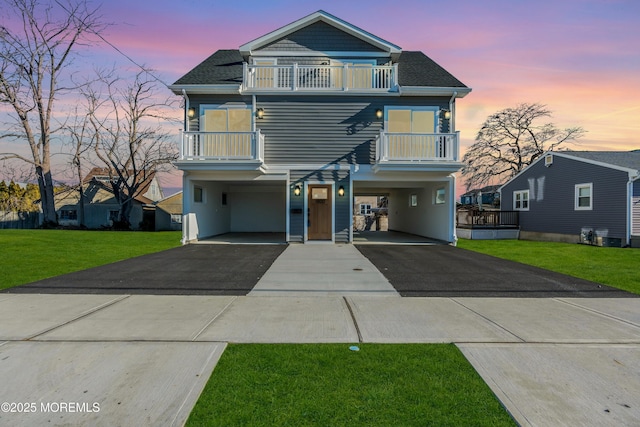 view of front of property featuring a balcony, a garage, and a lawn