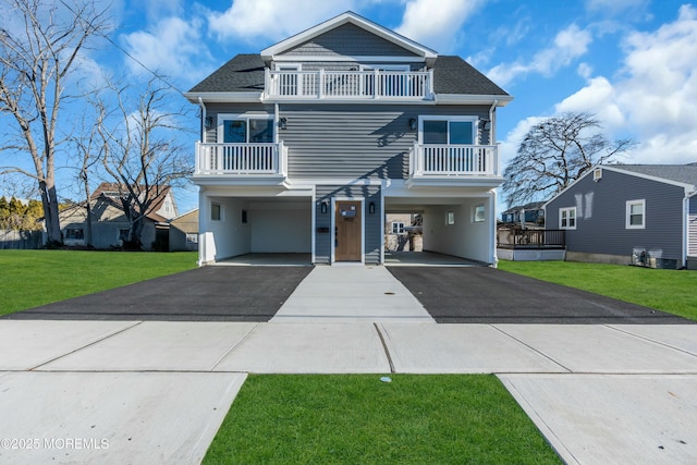 view of front facade with a carport, a balcony, and a front yard