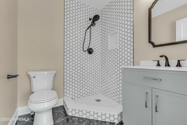 bathroom with toilet, tiled shower, and vanity