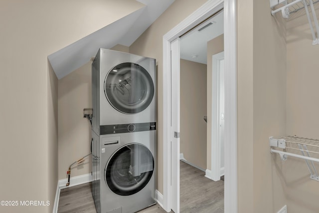 clothes washing area featuring stacked washing maching and dryer and hardwood / wood-style floors