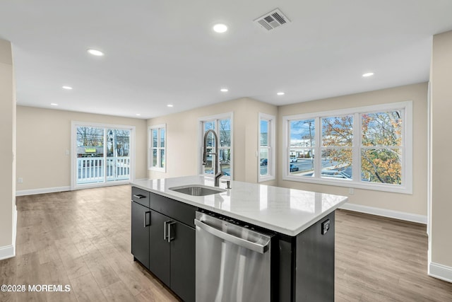 kitchen featuring stainless steel dishwasher, a kitchen island with sink, light wood-type flooring, and sink