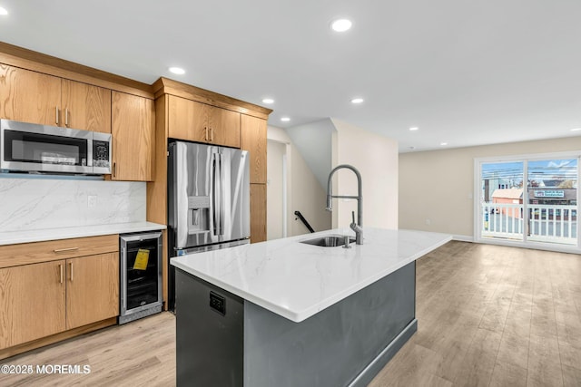 kitchen with stainless steel appliances, sink, an island with sink, decorative backsplash, and beverage cooler