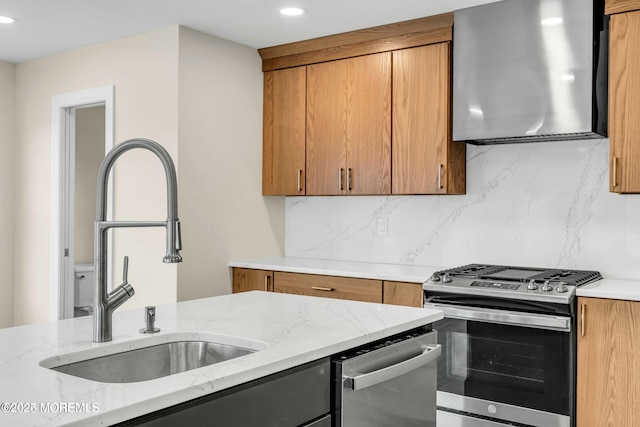 kitchen featuring stainless steel appliances, sink, wall chimney exhaust hood, tasteful backsplash, and light stone countertops