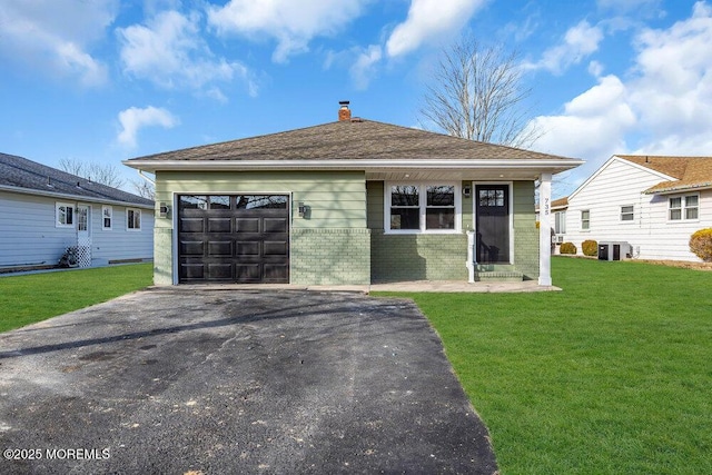 view of front of house featuring a front lawn, central air condition unit, and a garage