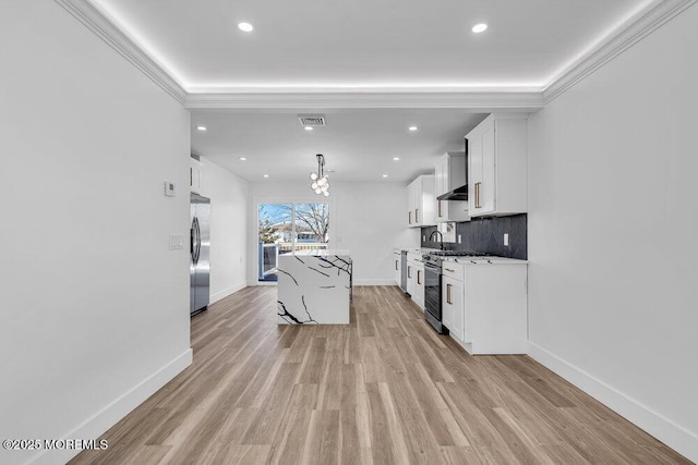 kitchen with pendant lighting, a center island, stainless steel appliances, white cabinets, and light stone counters