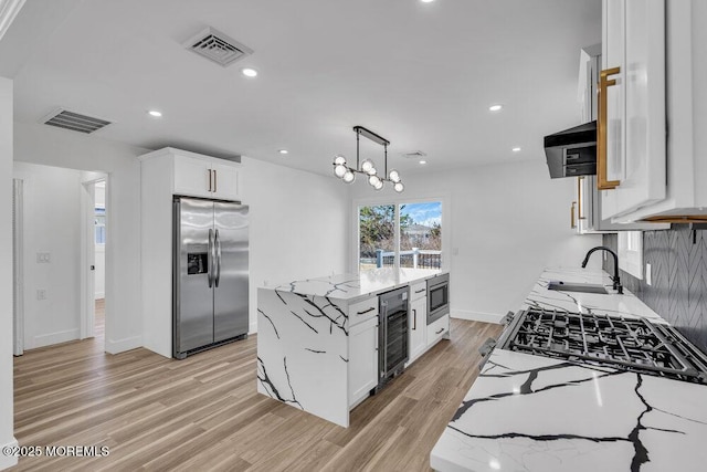 kitchen featuring light stone countertops, white cabinets, appliances with stainless steel finishes, and a center island