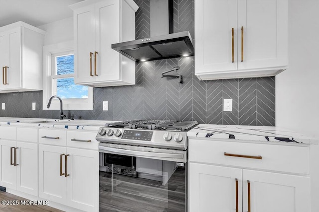 kitchen featuring white cabinetry, wall chimney exhaust hood, stainless steel gas stove, and light stone countertops