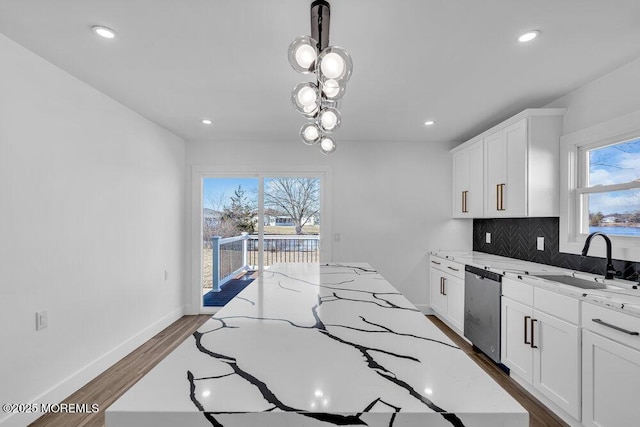 kitchen with stainless steel dishwasher, sink, white cabinetry, and a kitchen island