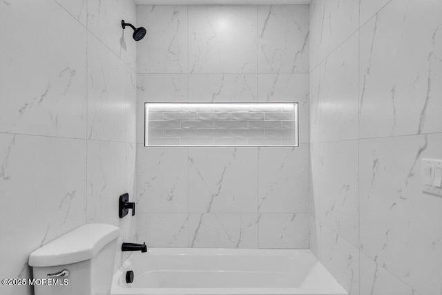 bathroom featuring tiled shower / bath combo and toilet