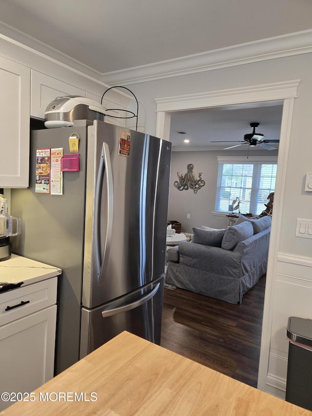 kitchen featuring white cabinetry, ceiling fan, stainless steel fridge, dark hardwood / wood-style flooring, and crown molding