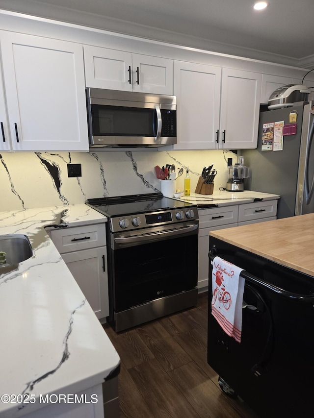 kitchen with dark wood-type flooring, stainless steel appliances, tasteful backsplash, crown molding, and white cabinetry