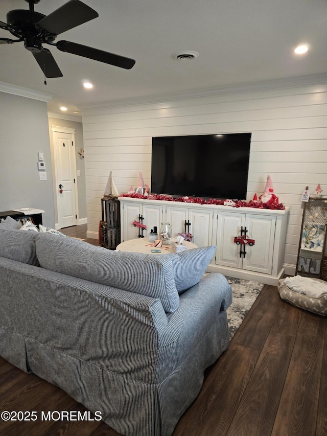 living room with ceiling fan, wood walls, ornamental molding, and hardwood / wood-style flooring