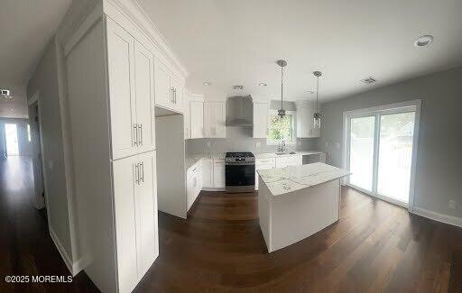 kitchen with pendant lighting, a kitchen island, white cabinets, stainless steel range oven, and dark hardwood / wood-style flooring