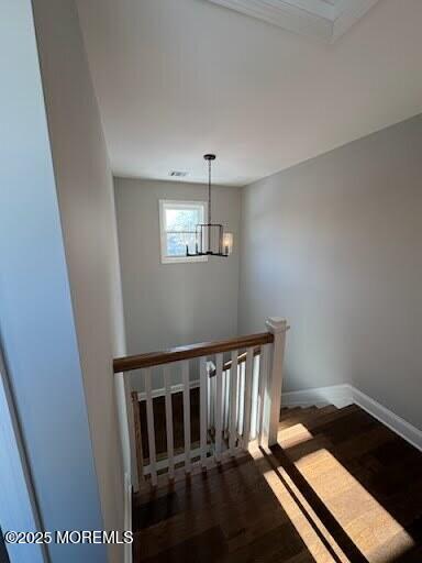 stairway with hardwood / wood-style floors and an inviting chandelier