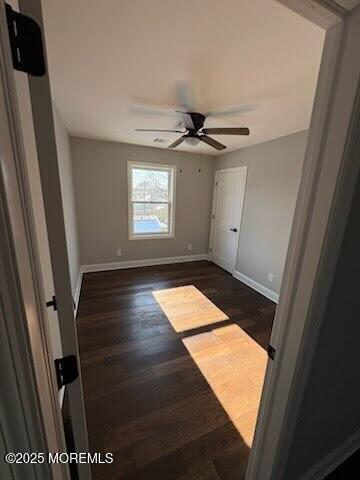 unfurnished bedroom with dark wood-type flooring and ceiling fan