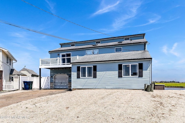 rear view of house featuring a balcony and a garage