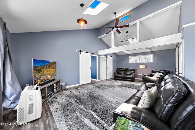 living room featuring ceiling fan, dark wood-type flooring, lofted ceiling with skylight, and a barn door