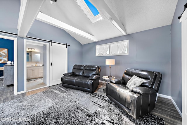 living room featuring dark hardwood / wood-style flooring, a textured ceiling, lofted ceiling with skylight, and a barn door