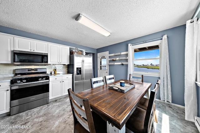 kitchen with a textured ceiling, white cabinetry, tasteful backsplash, and appliances with stainless steel finishes