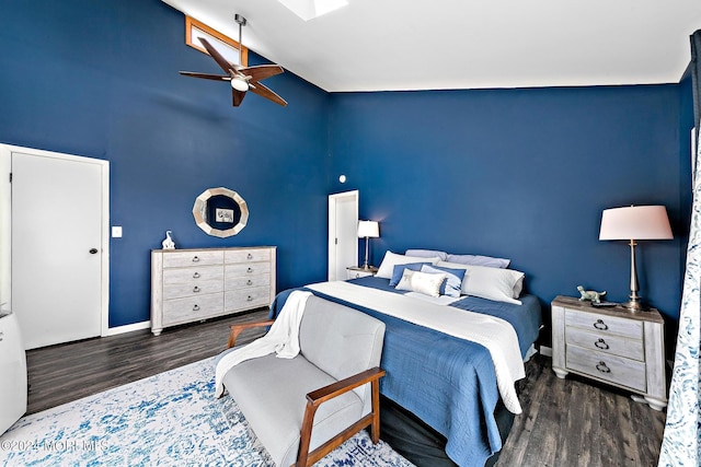 bedroom with ceiling fan, dark hardwood / wood-style floors, and vaulted ceiling with skylight