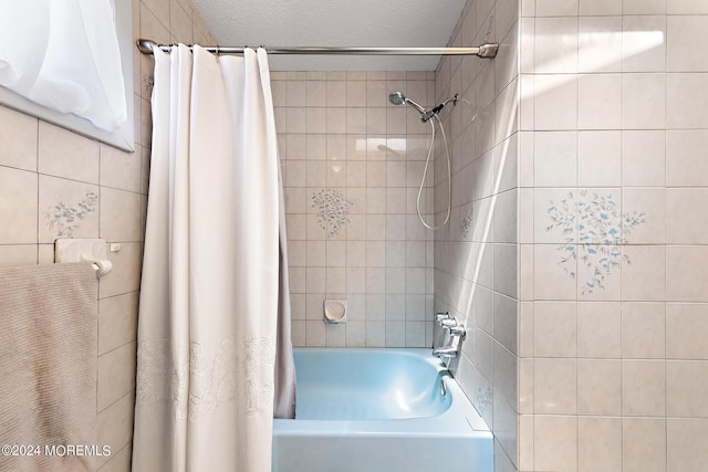 bathroom with a textured ceiling and shower / tub combo