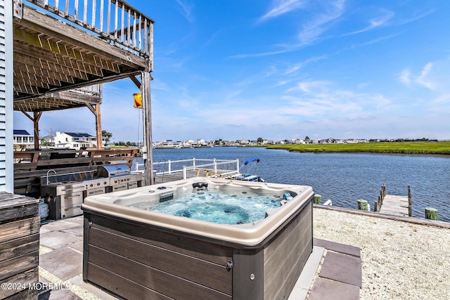 view of patio with a hot tub and a water view