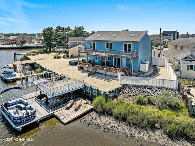 back of house with a hot tub and a deck with water view