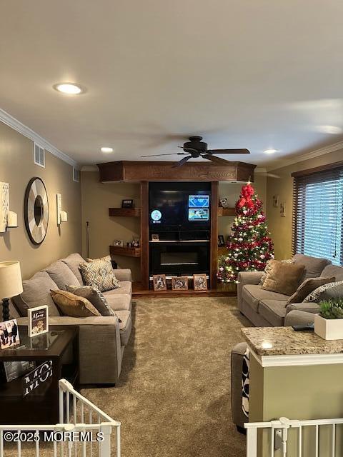 living room featuring ceiling fan, crown molding, and carpet flooring