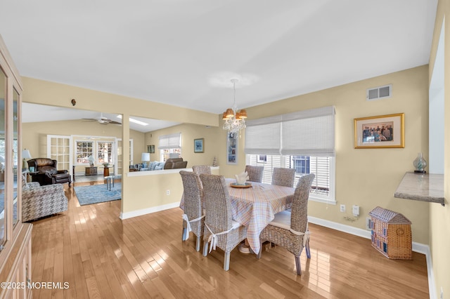 dining room with light wood-type flooring, vaulted ceiling, and ceiling fan with notable chandelier