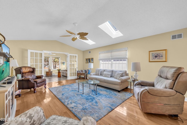 living room with french doors, a textured ceiling, ceiling fan, and light hardwood / wood-style flooring