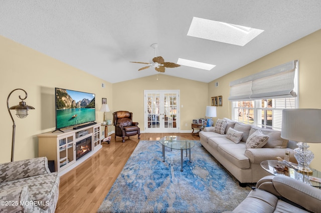 living room featuring ceiling fan, vaulted ceiling, a healthy amount of sunlight, and light hardwood / wood-style flooring