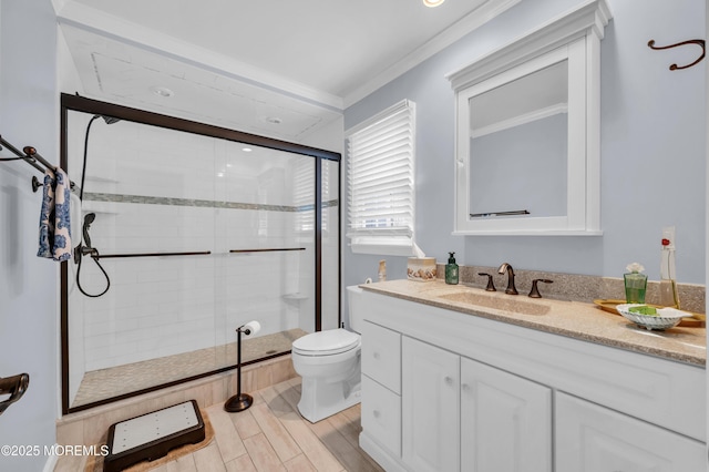 bathroom featuring ornamental molding, a shower with door, vanity, and toilet