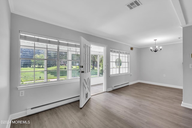 spare room featuring wood-type flooring, a baseboard radiator, crown molding, and a notable chandelier