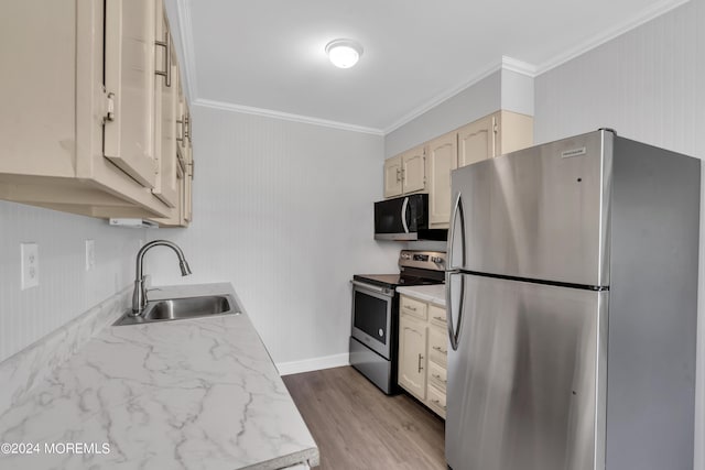 kitchen with light hardwood / wood-style floors, stainless steel appliances, ornamental molding, sink, and cream cabinets