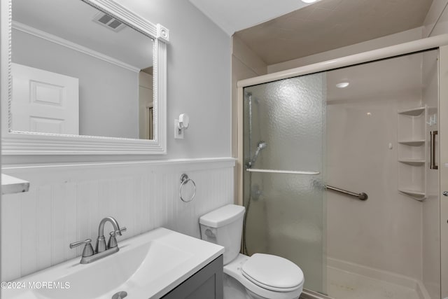 bathroom with toilet, crown molding, a shower with shower door, and vanity