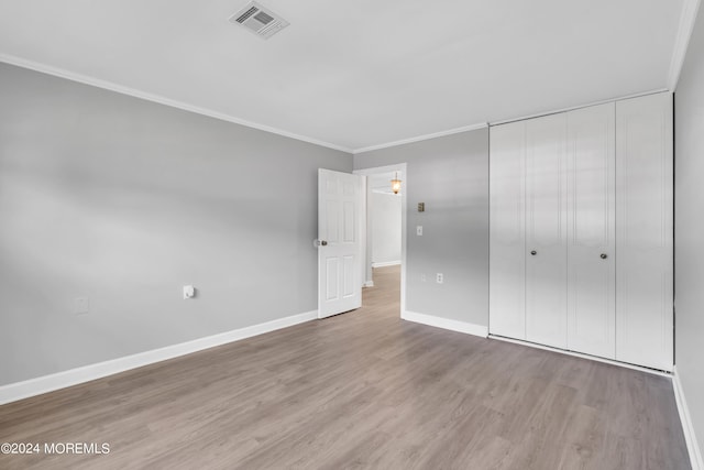 unfurnished bedroom featuring a closet, ornamental molding, and light hardwood / wood-style flooring