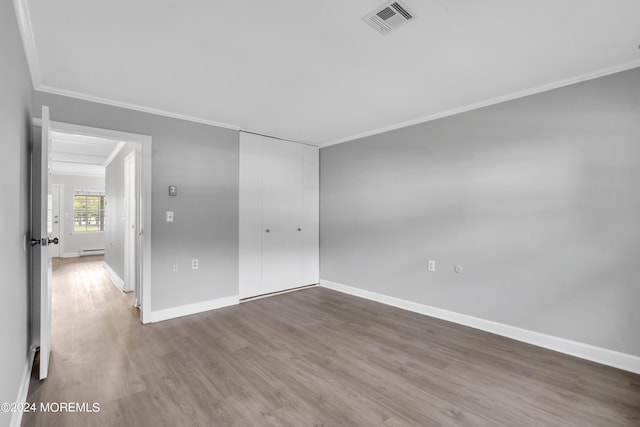 unfurnished room featuring hardwood / wood-style floors, baseboard heating, and ornamental molding