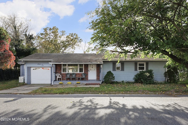 ranch-style home with covered porch, ac unit, and a garage