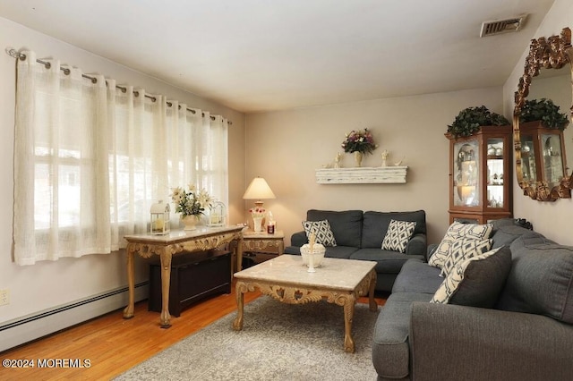 living room featuring a wealth of natural light, a baseboard radiator, and wood-type flooring